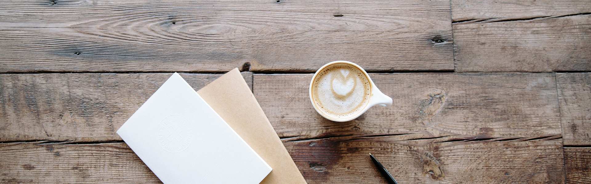 Coffee, blank cards and a pen on a wooden table